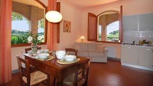 Un comedor con una mesa de madera dispuesta para cuatro personas, un sofá y una cocina al fondo.