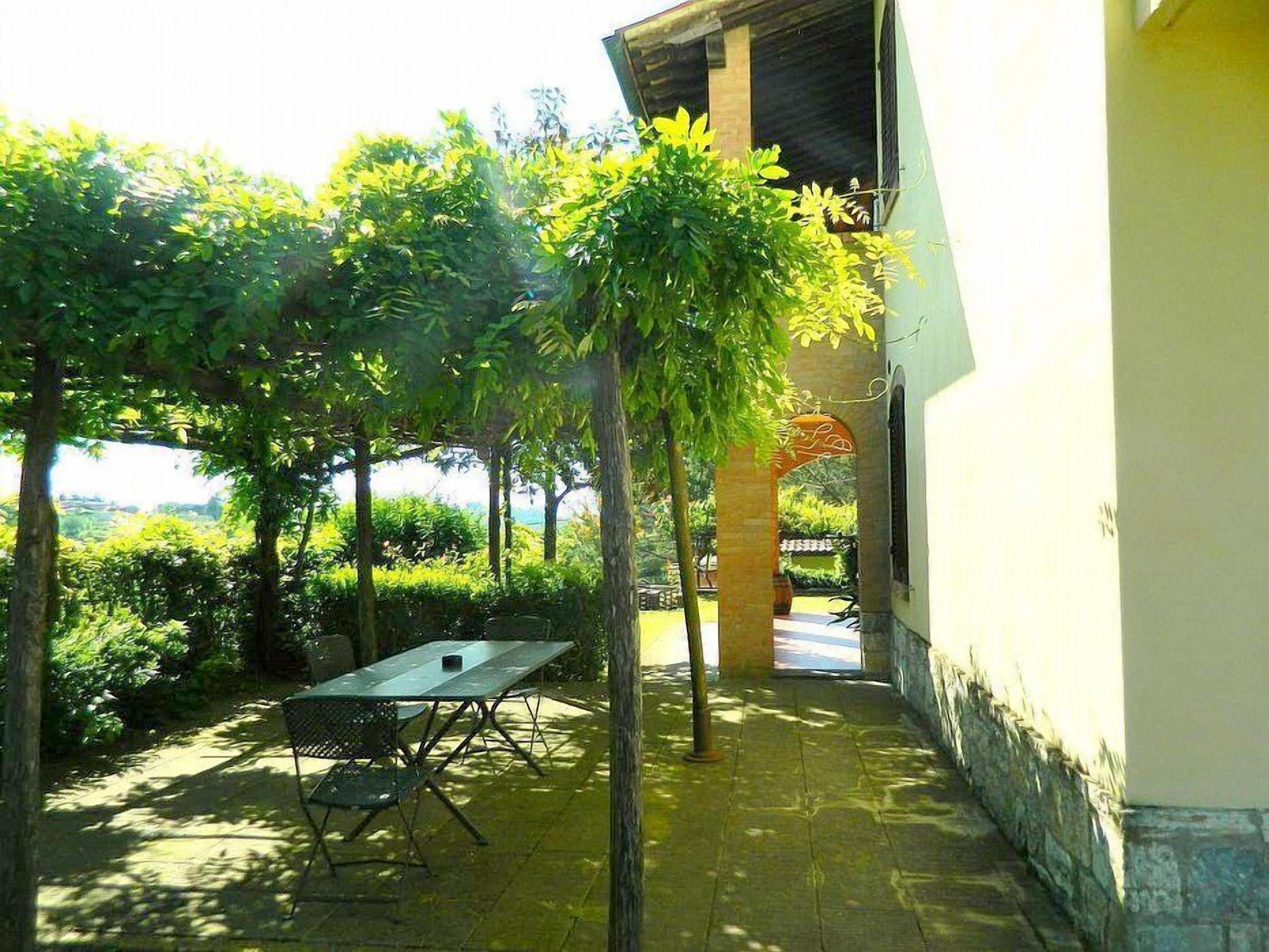 An outdoor patio area with a table and chairs, surrounded by lush greenery and a view of the sea.