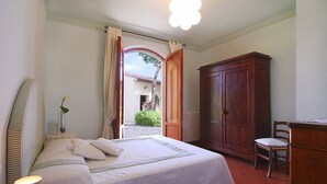 Un dormitorio con cama, un armario de madera, una silla y un escritorio.
