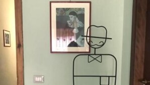 A room with a framed picture on the wall, a door, and a checkered floor.