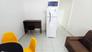 Une petite cuisine équipée d’un réfrigérateur, d’un bureau en bois et de deux chaises.