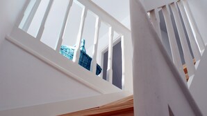 Una escala amb un fanal i barana de fusta i color blanc.