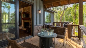 Une terrasse couverte, aménagée avec des meubles en osier, une table en verre et un barbecue.