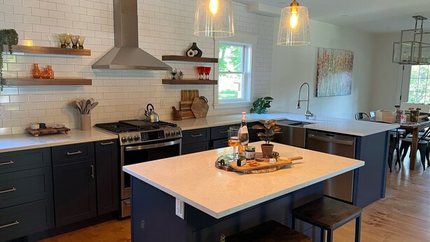 Cocina moderna con una isla central, armarios oscuros e iluminación colgante.