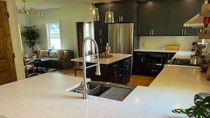 Una cocina moderna con armarios oscuros, un refrigerador de acero inoxidable y una isla grande con un lavamanos.