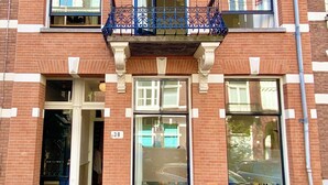 Un edificio de ladrillo de dos pisos con un balcón, una puerta con el número 38 y bicicletas estacionadas adelante.