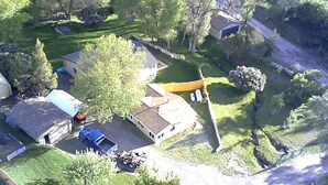 Vue aérienne d’un quartier résidentiel avec des maisons, une allée et un véhicule bleu garé devant l’une des maisons.