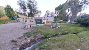 Un quartier résidentiel avec une petite maison, une cour verdoyante et un ruisseau.