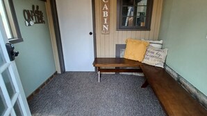 Une petite cabane accueillante, avec un banc en bois, une porte et une fenêtre.