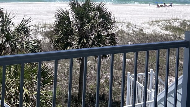 A balcony with a view of a beach and ocean.