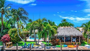 Un complexe hôtelier tropical doté d’une structure à toit de chaume, d’une piscine et d’un quai avec des kayaks.