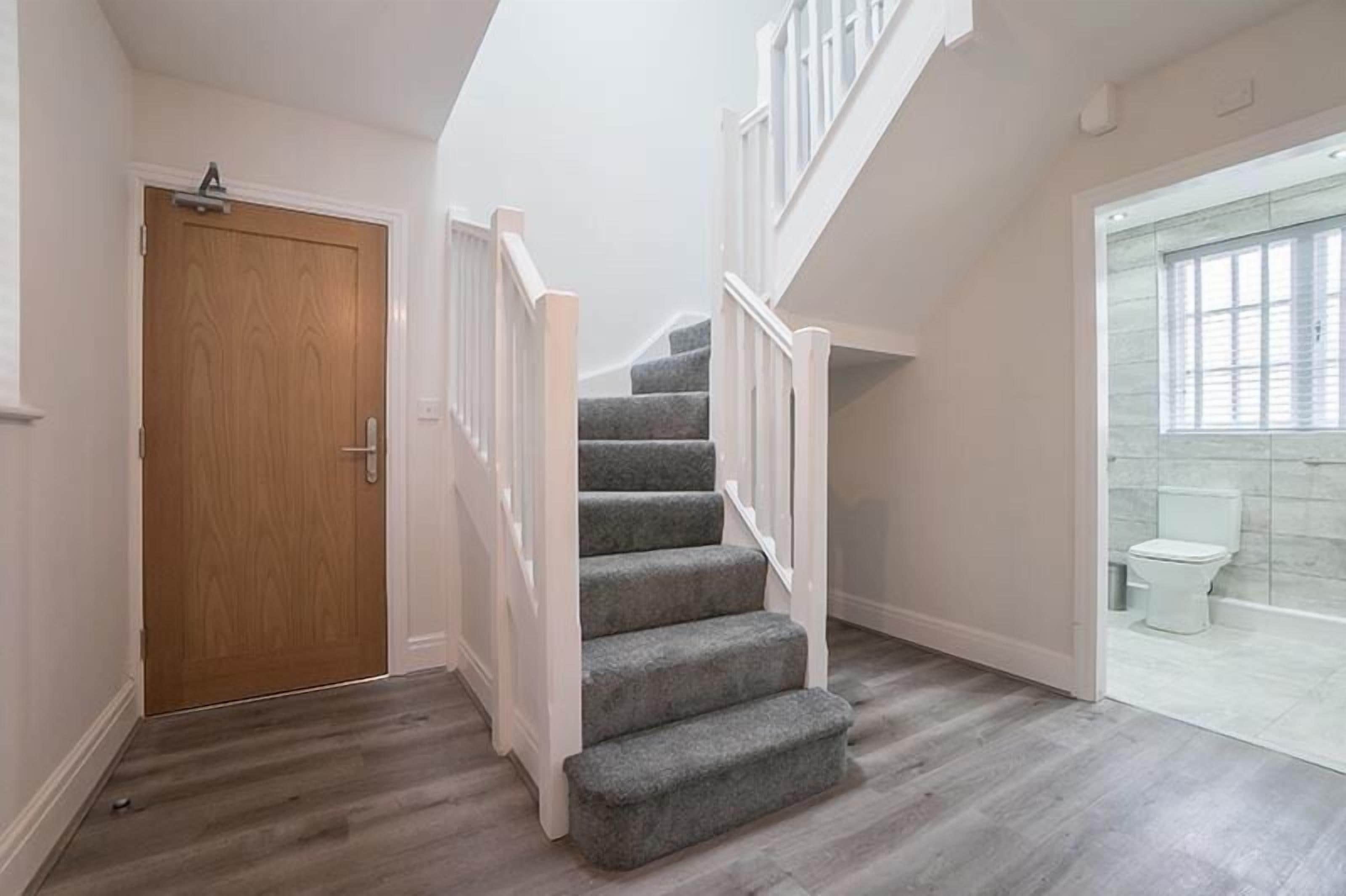 A staircase with carpeted steps and white railings leading to a second floor.