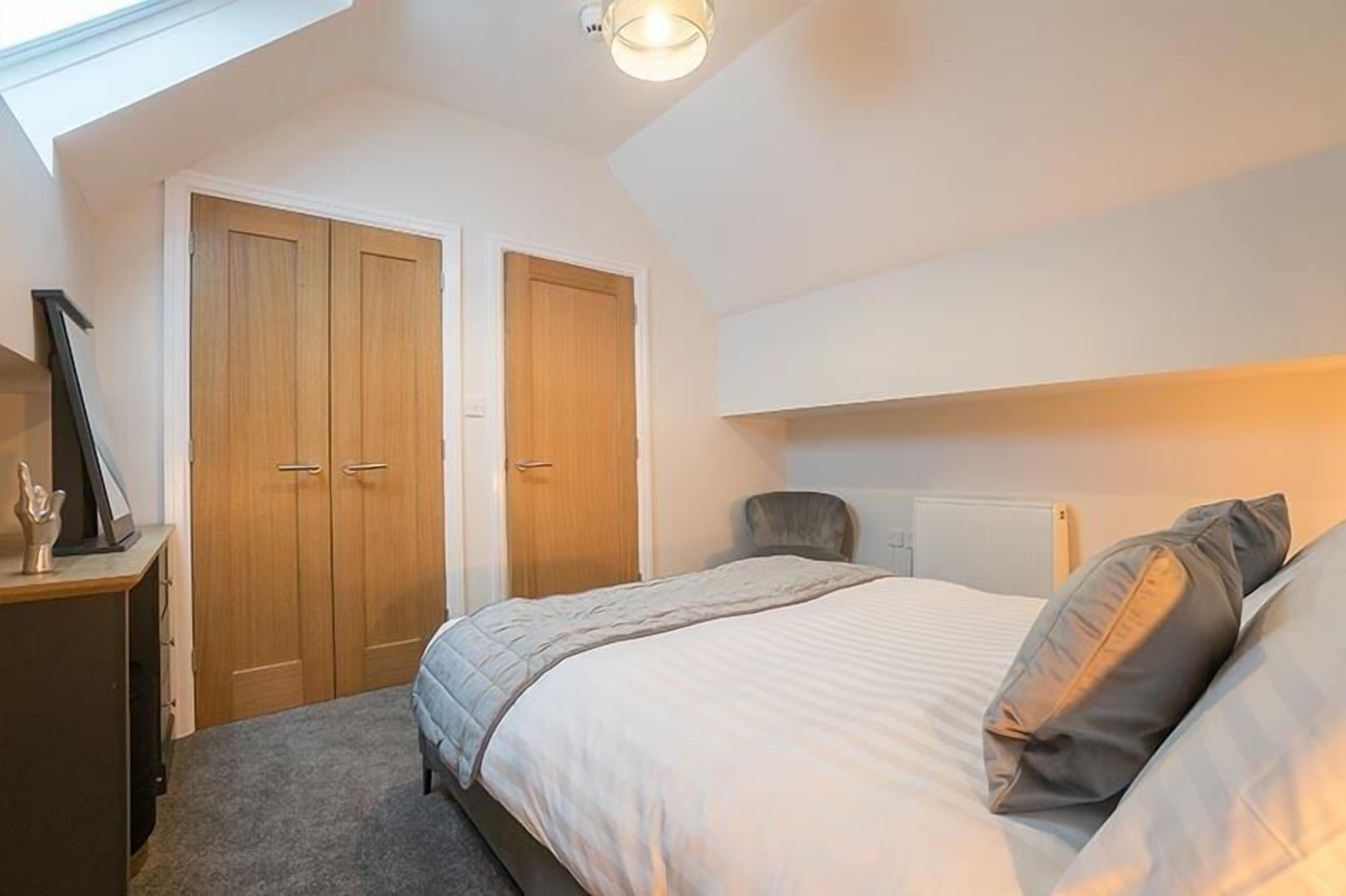A bedroom with a bed, a desk, and two wardrobes.