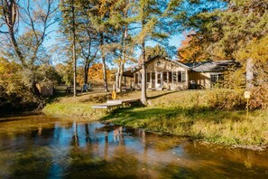 A rustic cabin by a calm river, surrounded by trees and a wooden fence. - Private fishing, perfect cabin vacation (Kaleva)
