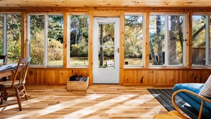 L’intérieur d’un chalet en bois est doté de grandes fenêtres, d’un coin repas et d’un espace salon.