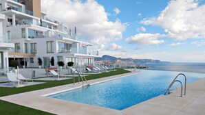 Ein modernes Hotel mit Pool, Liegestühlen und Meerblick.