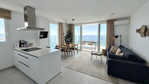 Eine moderne Küche mit einer großen Kochinsel, ein Essbereich mit Blick und ein Wohnbereich mit Sofa und Lampe.