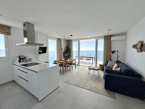Una cocina moderna con una isla grande, un comedor con vistas y una sala de estar con sofá y lámpara.