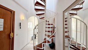 Una escalera de caracol con barandillas blancas y escalones de madera, que conduce a un piso superior.
