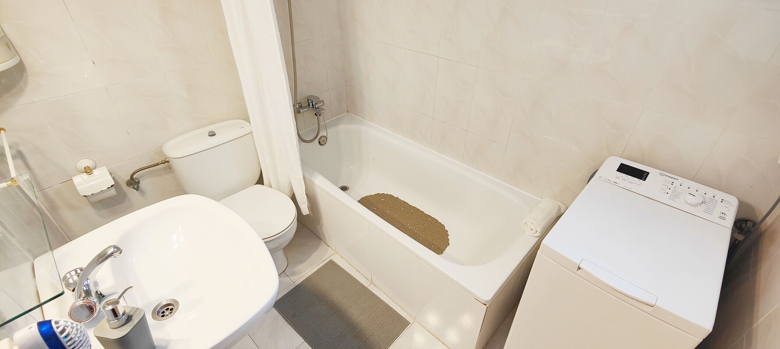Une salle de bain équipée de toilettes, d’un lavabo, d’une baignoire et d’un lave-linge.