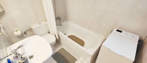 Une salle de bain équipée de toilettes, d’un lavabo, d’une baignoire et d’un lave-linge.
