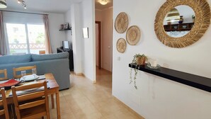 Un coin repas avec une table dressée pour quatre personnes, un canapé en arrière-plan et des œuvres d’art décoratives au mur.