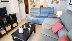 Un salon avec un canapé, une table basse, un téléviseur et une bibliothèque.