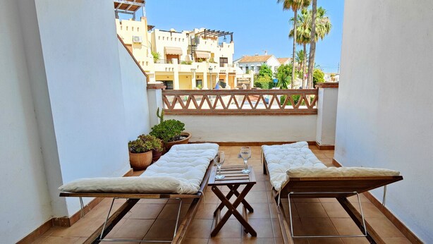 Un balcon avec deux chaises longues, une petite table et des plantes en pot.