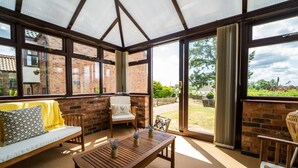 A sunroom with a wooden table, a sofa, and a chair.