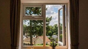 A window with a view of a river, houses, and trees.