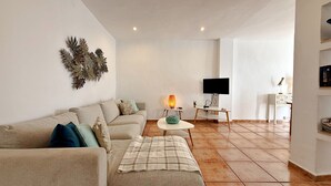 Ein Wohnzimmer mit einer Couch, einem Couchtisch, einem Fernseher und einer Wanddekoration.