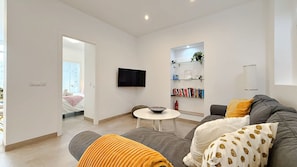 A modern living room with a sofa, a coffee table, a TV, and a bookshelf.