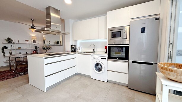 A modern kitchen with a built-in washing machine, a stainless steel refrigerator, and a microwave. - AP310 - Colon Bajo (Nerja)