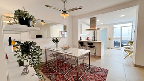 A modern kitchen with a dining area, large windows, and a ceiling fan. - AP310 - Colon Bajo (Nerja)