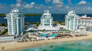 Ein Resort mit mehreren Hochhäusern, einem Strand und einem Poolbereich.
