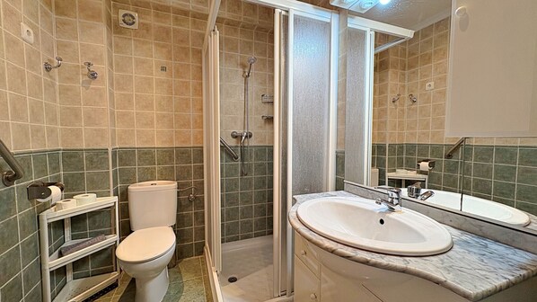 A bathroom with a toilet, shower, sink, and mirror. - AP370 - Bahia (Nerja)