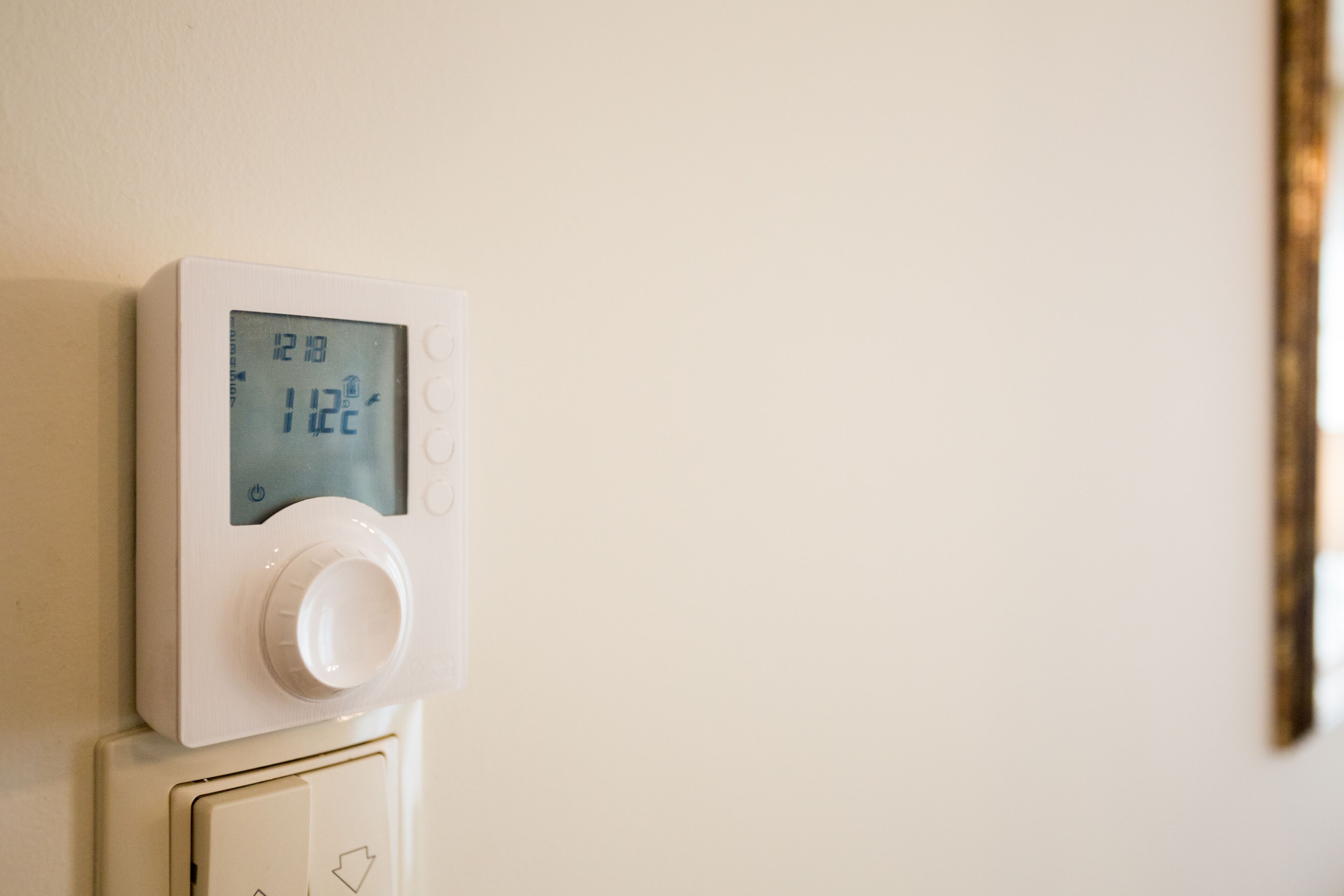 Un termostato con pantalla digital que indica una temperatura de 12 grados Celsius.