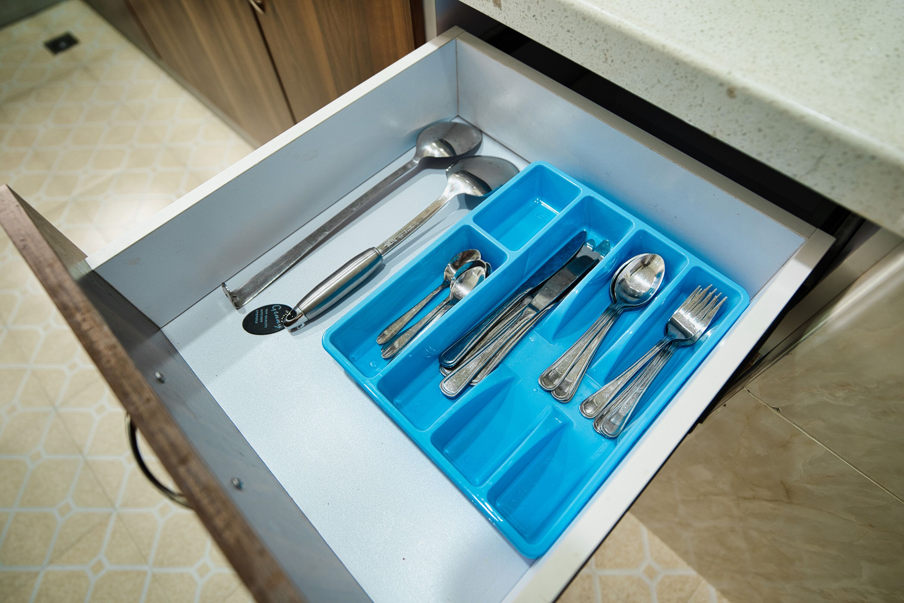 A drawer with compartments containing various kitchen utensils.