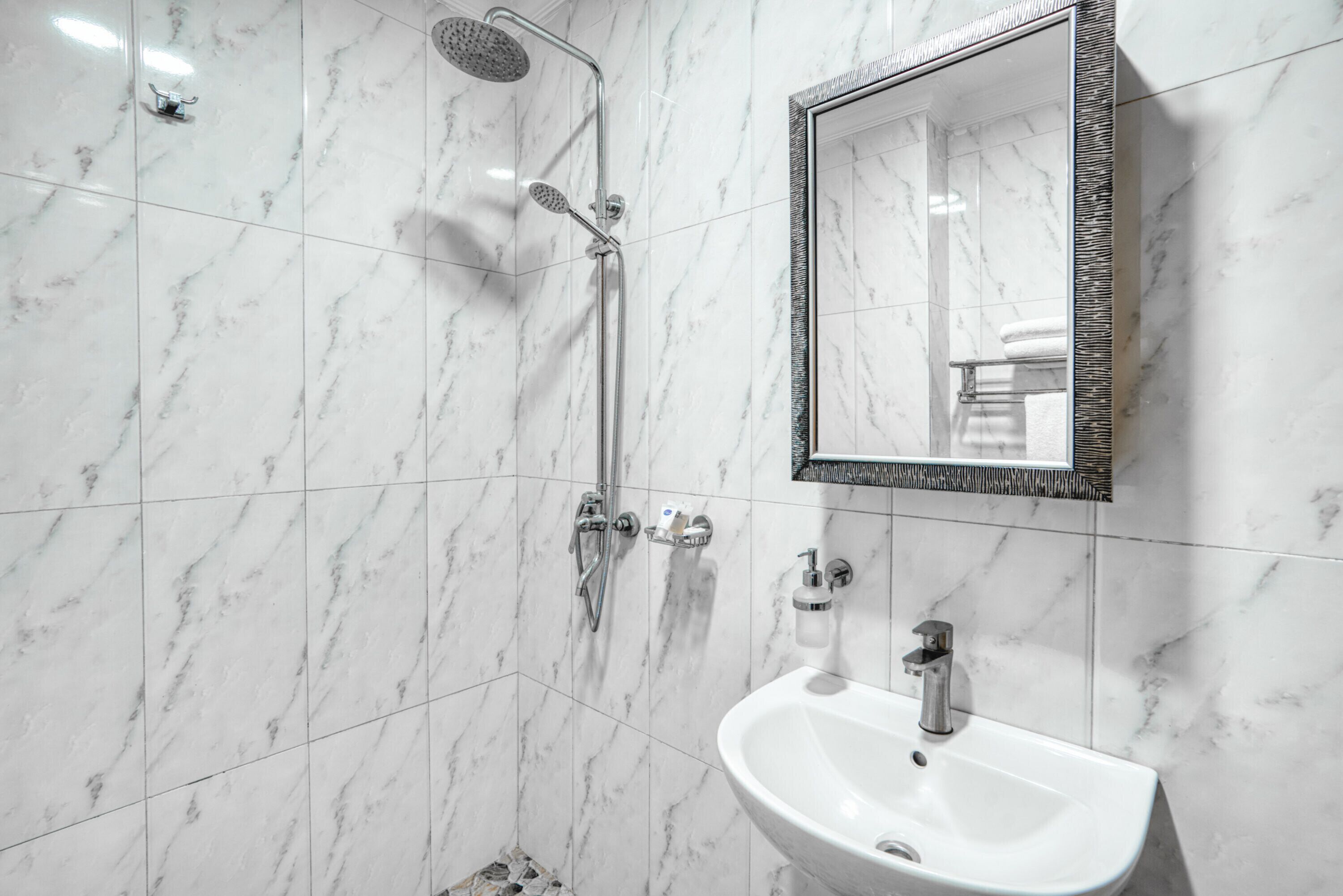 A bathroom with a shower, sink, and mirror.