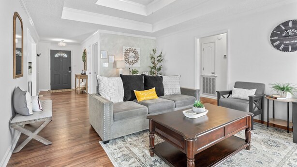 A spacious living room with a grey sofa, a wooden coffee table, and a grey armchair. A large clock is on the wall, and there is a door leading to another room. - The best of Huntsville: Mountain view & Attraction. (Huntsville)