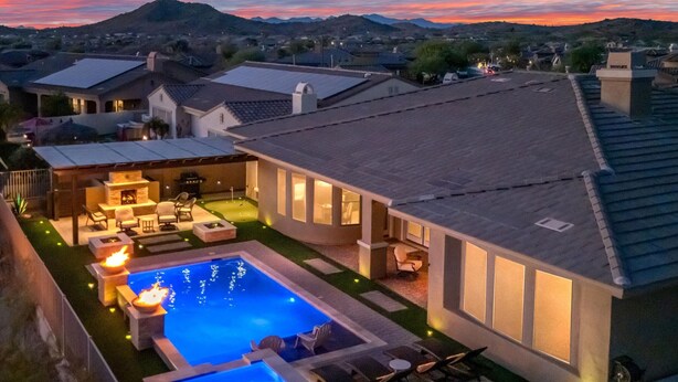 Une propriété résidentielle dotée d’une piscine, d’un espace extérieur aménagé et d’une terrasse bien éclairée.