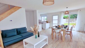 Un salon moderne avec un canapé, une table à manger et une cuisine en arrière-plan.