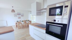 Une cuisine moderne équipée d’un four à micro-ondes et d’un four encastrés, ainsi que d’une table à manger en bois avec des chaises.