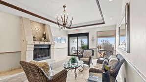A spacious indoor area with wicker furniture, a glass table, a fireplace, and a chandelier.