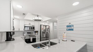 A modern kitchen with white cabinetry, stainless steel appliances, and a white countertop.