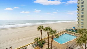A beachfront hotel with a swimming pool, palm trees, and ocean views.