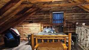 Une chambre confortable dans un chalet en rondins, avec un lit en bois, un banc et une fenêtre avec des rideaux.
