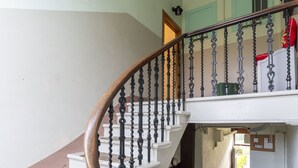 Un escalier avec des marches blanches et des balustrades noires, menant à un palier où se trouve un objet rouge sur une étagère blanche.