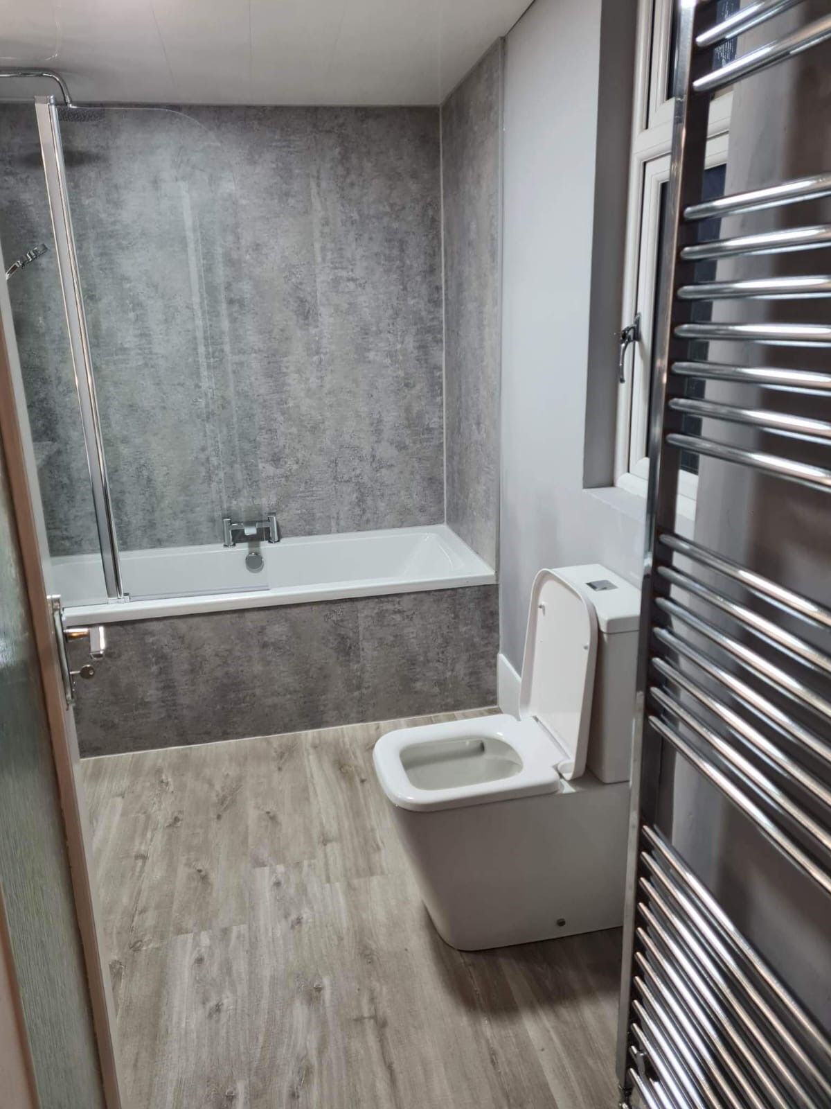 Een moderne badkamer met een bad, toilet en douche.