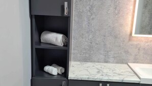 Une salle de bain avec des meubles sombres, un comptoir en marbre et un porte-serviettes.